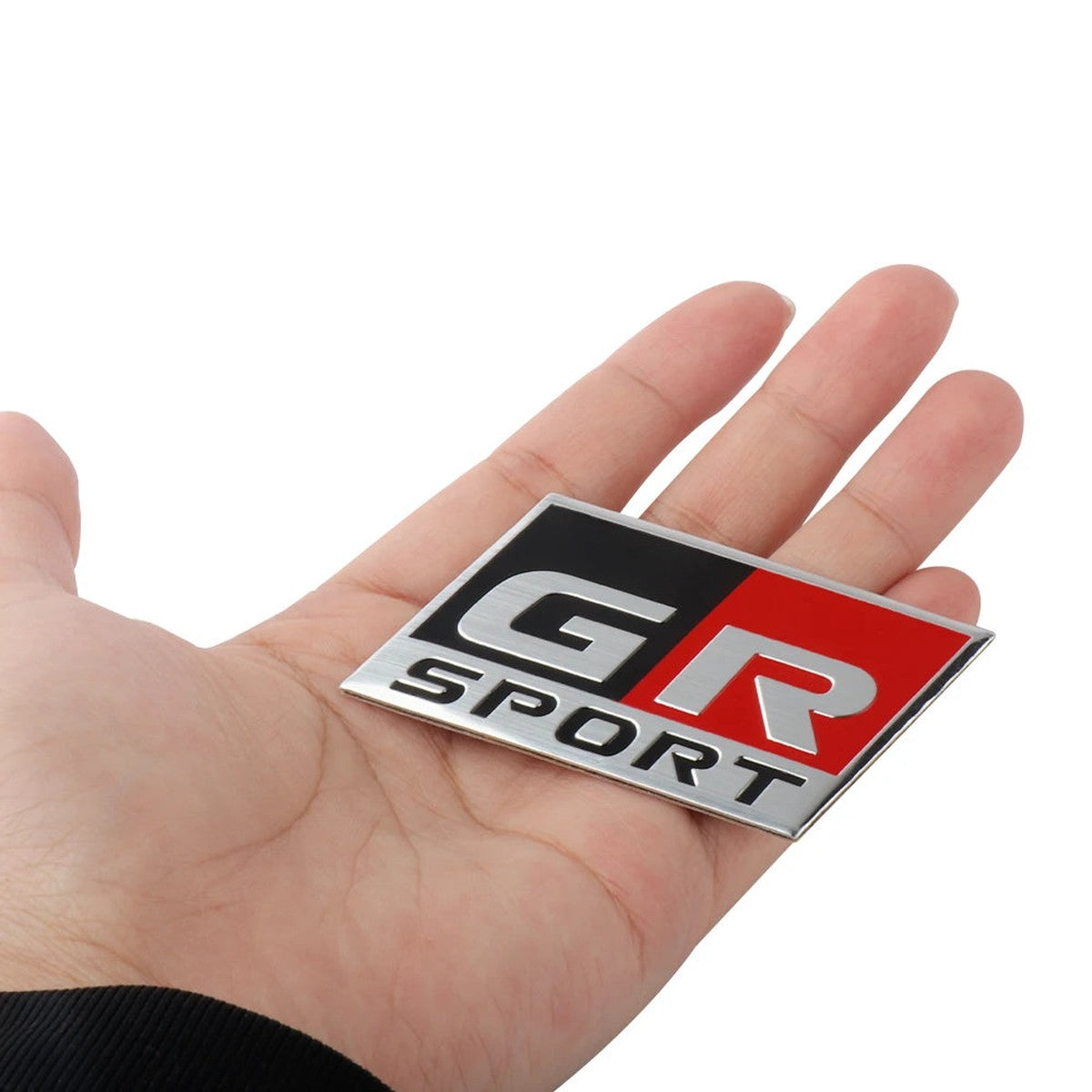 GR Sport-style aluminum badge held in hand