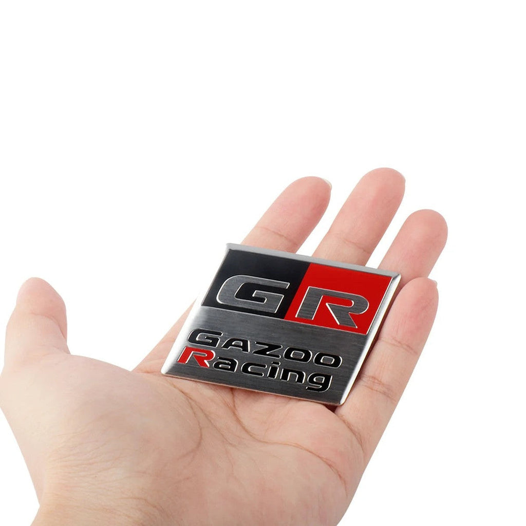 GR Gazoo Racing-style square aluminum badge held in hand
