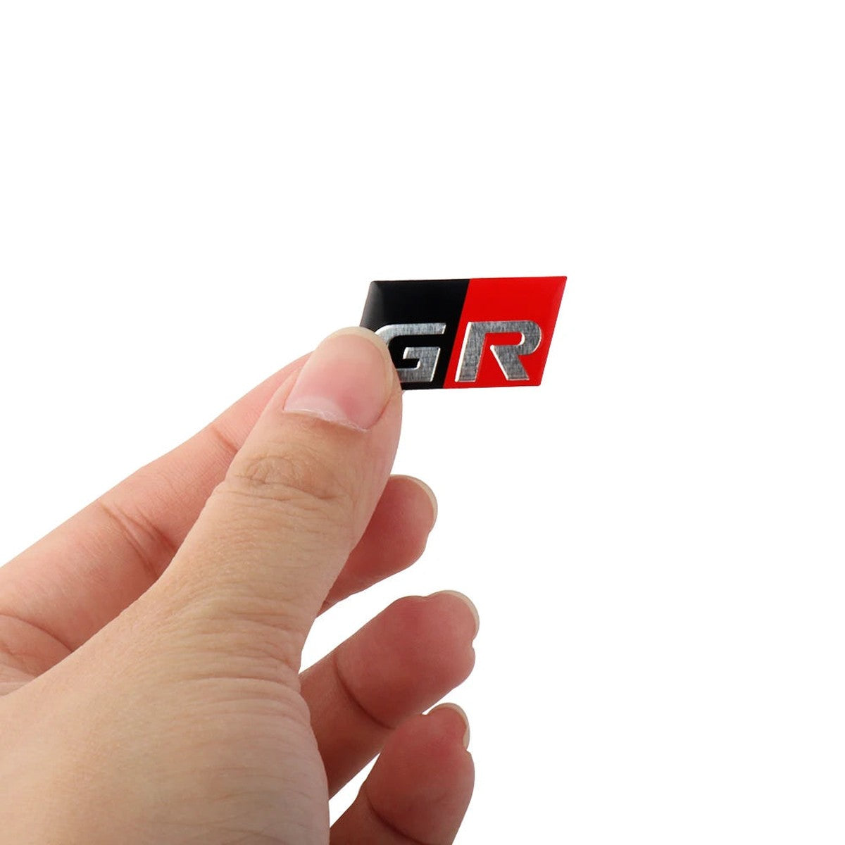 Small GR-style aluminum badge held between fingers