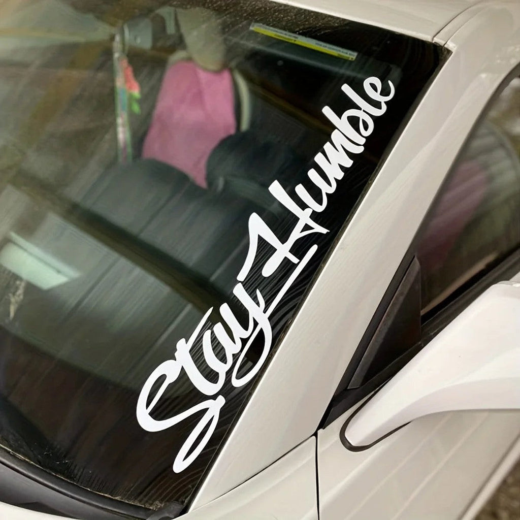 White Stay Humble script decal on a car windshield pillar