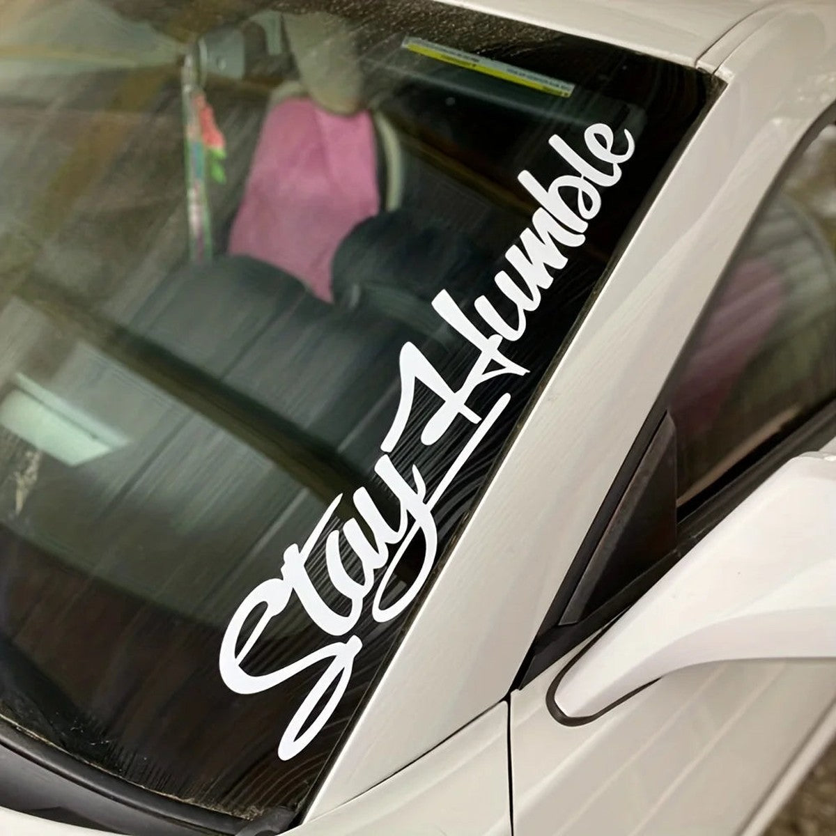 White Stay Humble script decal on a car windshield pillar