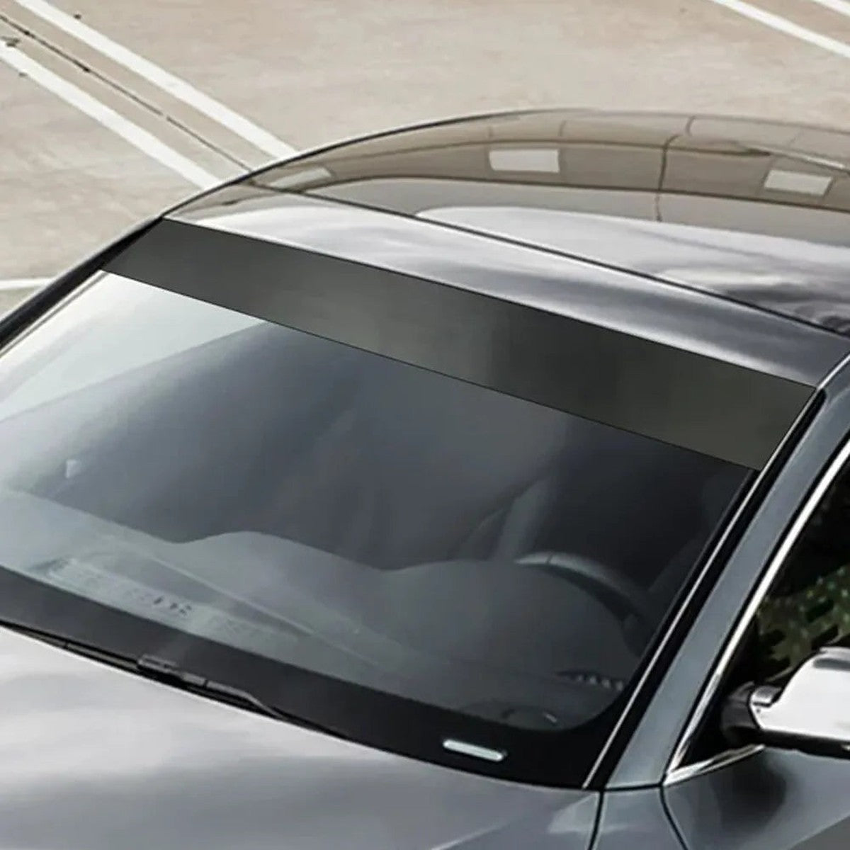 Black vinyl windshield sun strip on a gray car, side angle