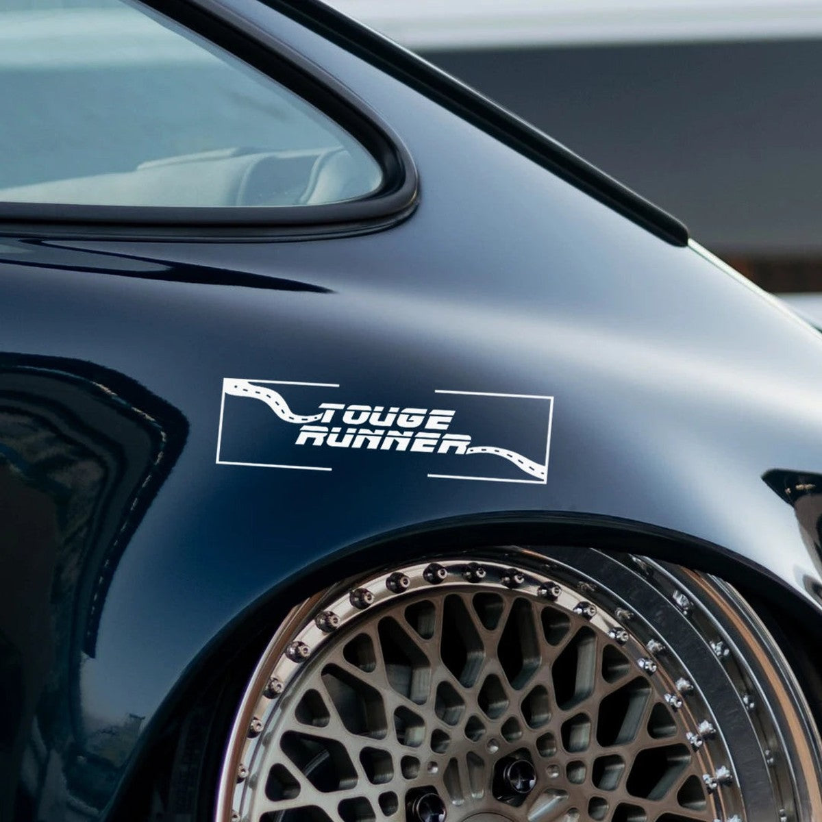 White Touge Runner slap sticker on the rear fender of a dark coupe