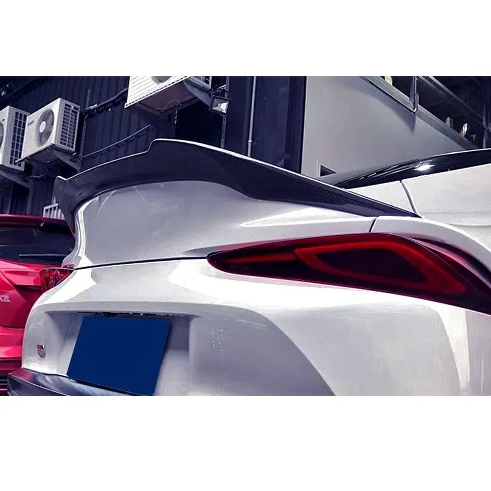 Carbon ducktail spoiler installed on a white GR Supra A90, rear three-quarter view